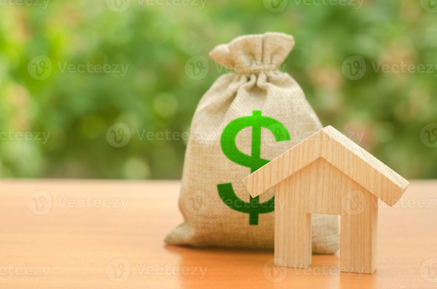 Wooden house figurine and money bag on the background of nature. Mortgage loan for the purchase of housing, construction or modernization. Budget, subsidized funds. Tax policy, building maintenance. photo