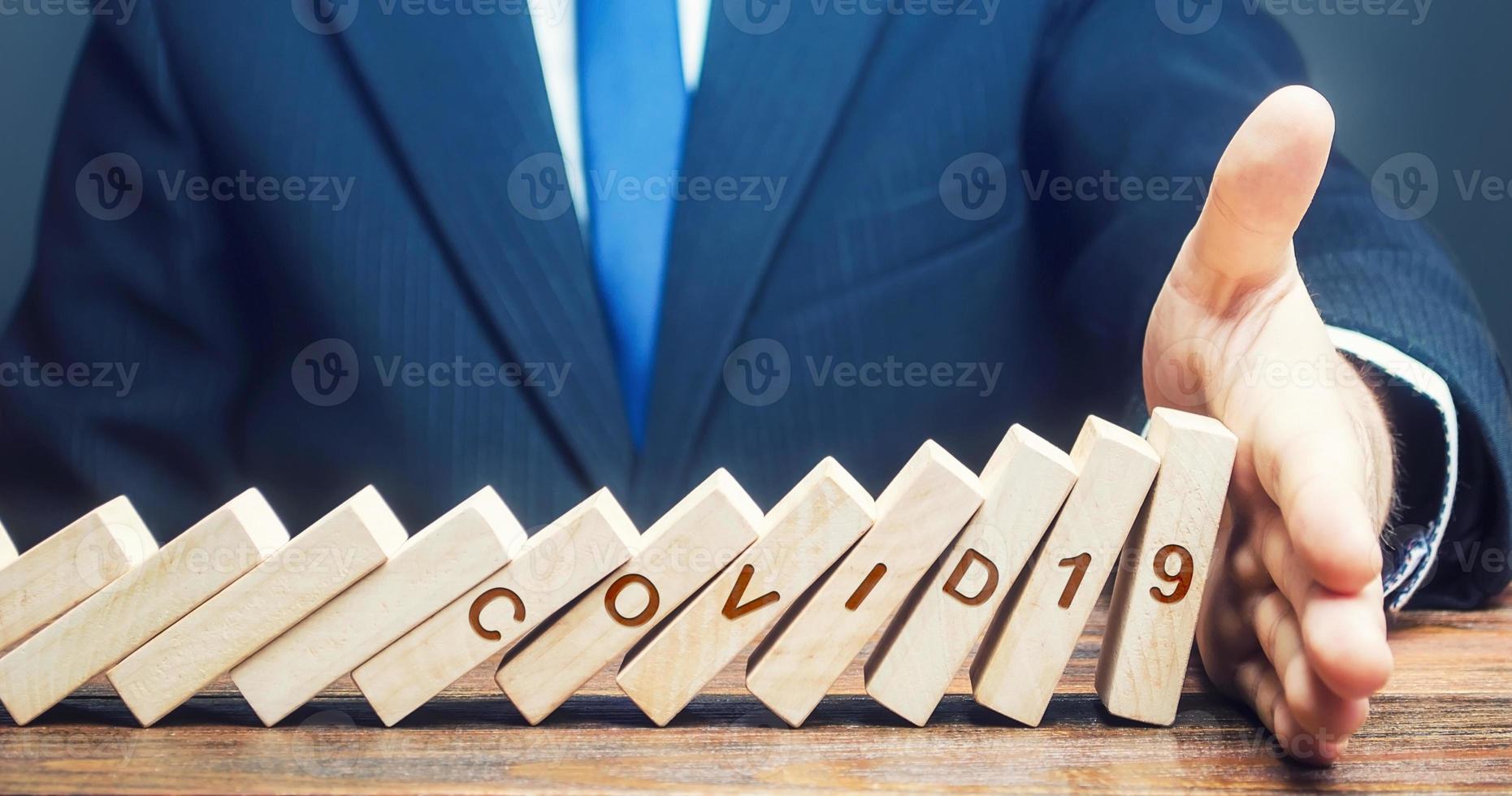Man stops fall of dominoes represents pandemic COVID-19 virus. Stop spread coronavirus exponential growth epidemic. Create tough measures, take control on situation. Stop new infections. Quarantine photo