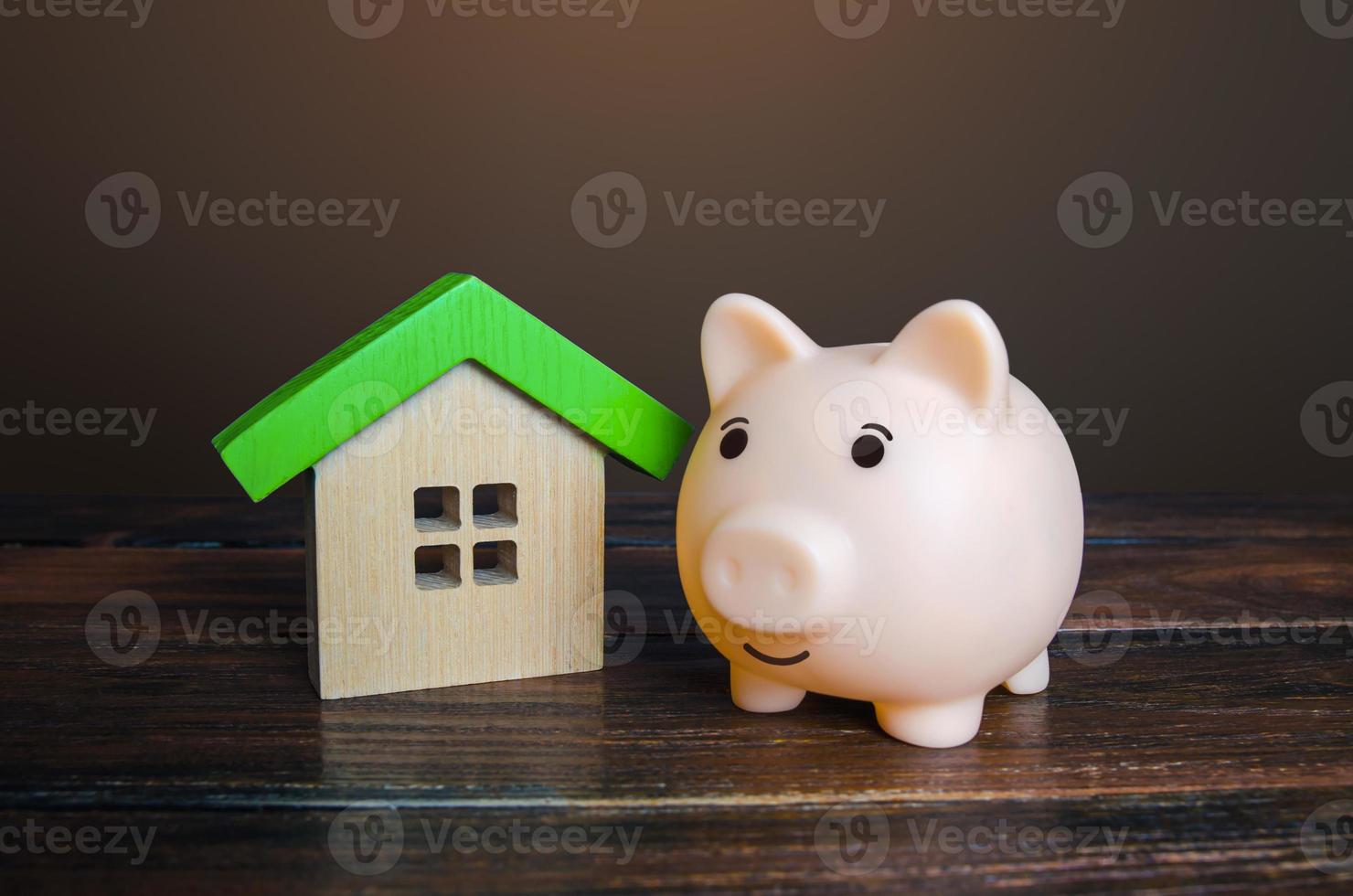 Piggy bank near a house. Savings on household bills, energy saving technologies. Save up for a new house. Mortgage loan. Maintenance, property improvement. Real estate market. Buying or selling. photo