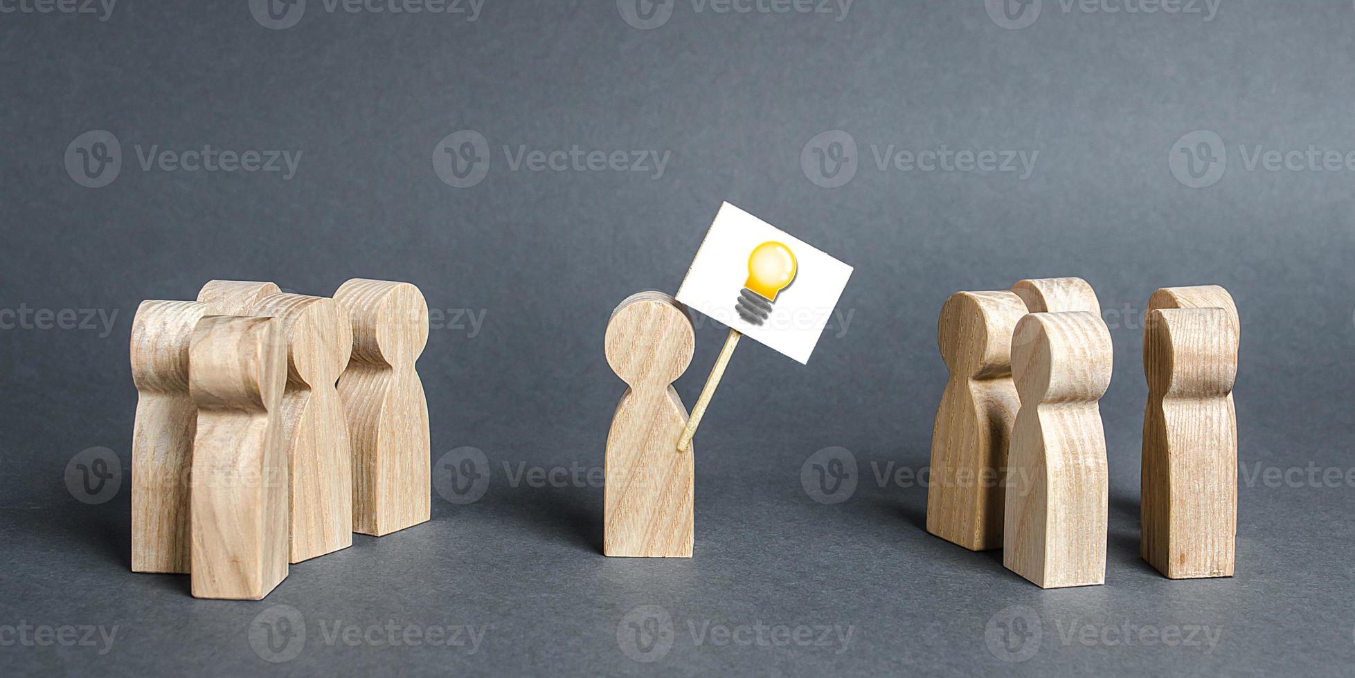 A man with a poster with a picture of the idea bulb refers to a crowd of people. The concept of proposing a new idea and option, a fresh look at the problem and finding a solution. Ambition photo