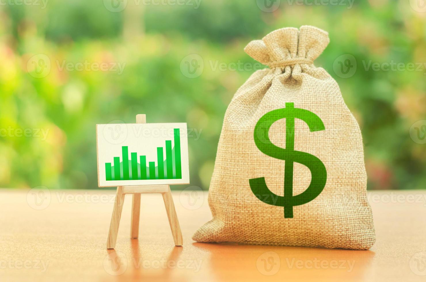 bolsa de dinero con símbolo de dólar y un stand con un gráfico de tendencia de crecimiento verde. aumentar las ganancias y la riqueza. crecimiento de los salarios. condiciones favorables para los negocios. atracción de inversiones. prestamos y subvenciones foto