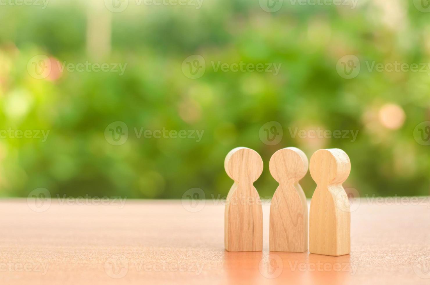 three wooden figures of people stand on the background of nature. Communication, meeting place. conduct a conversation. Discussion of cases and plans, society and community. Place for text. photo