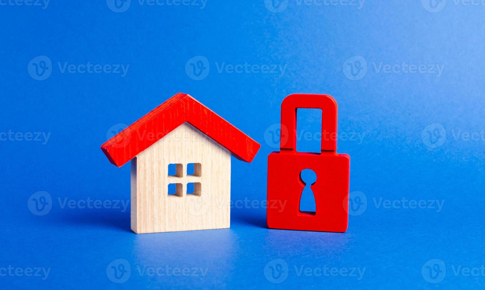 A wooden house and a red padlock. Unavailable and expensive real estate. house Insurance. Security and safety. Confiscation for debts. alarm system. seizure of property. Protection of property rights. photo