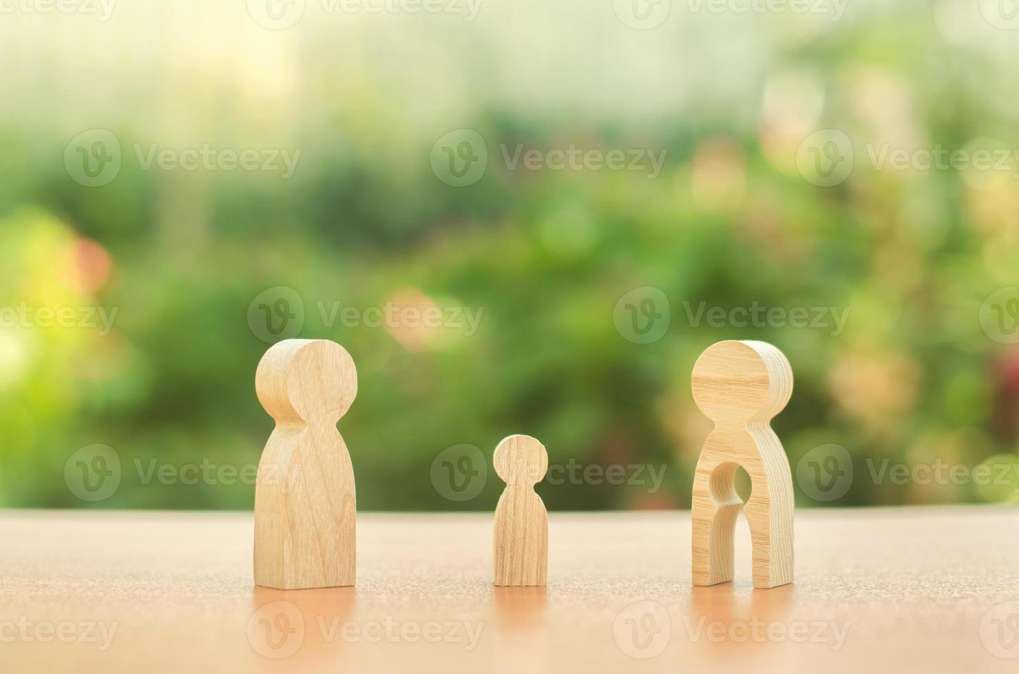 Childs figure stands between father and mother. The child chooses which parent to live with after their divorce. Guardianship over child. Taking into account the interest of child, payment of alimony photo