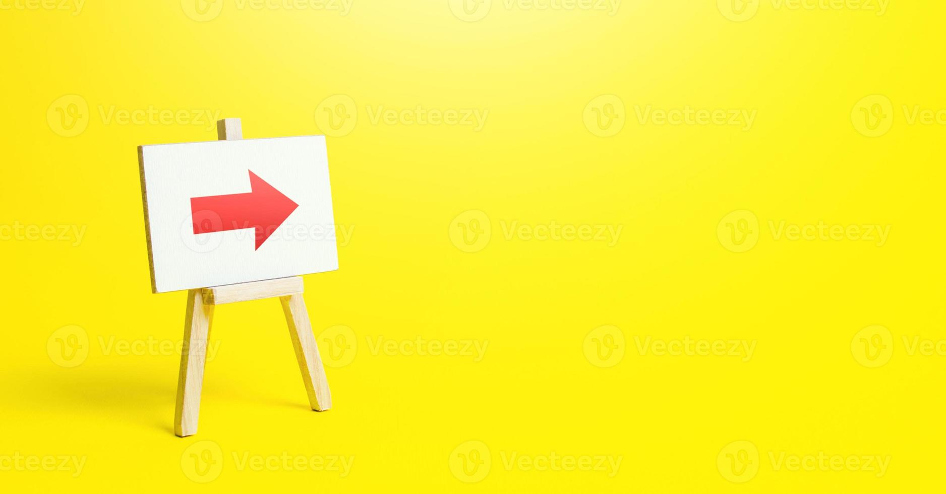Easel with a red right arrow on a yellow background. Sign of direction. Advertising of the location of a store or outlet. Minimalism. Restriction of movement. Short road. photo