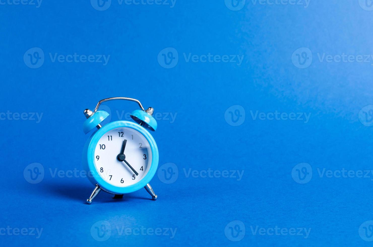 A blue alarm clock on a blue background. Limited offer and over time. Planning and discipline. waiting for a meeting. Punctuality. business planning. Life duration and health, increase your age. photo