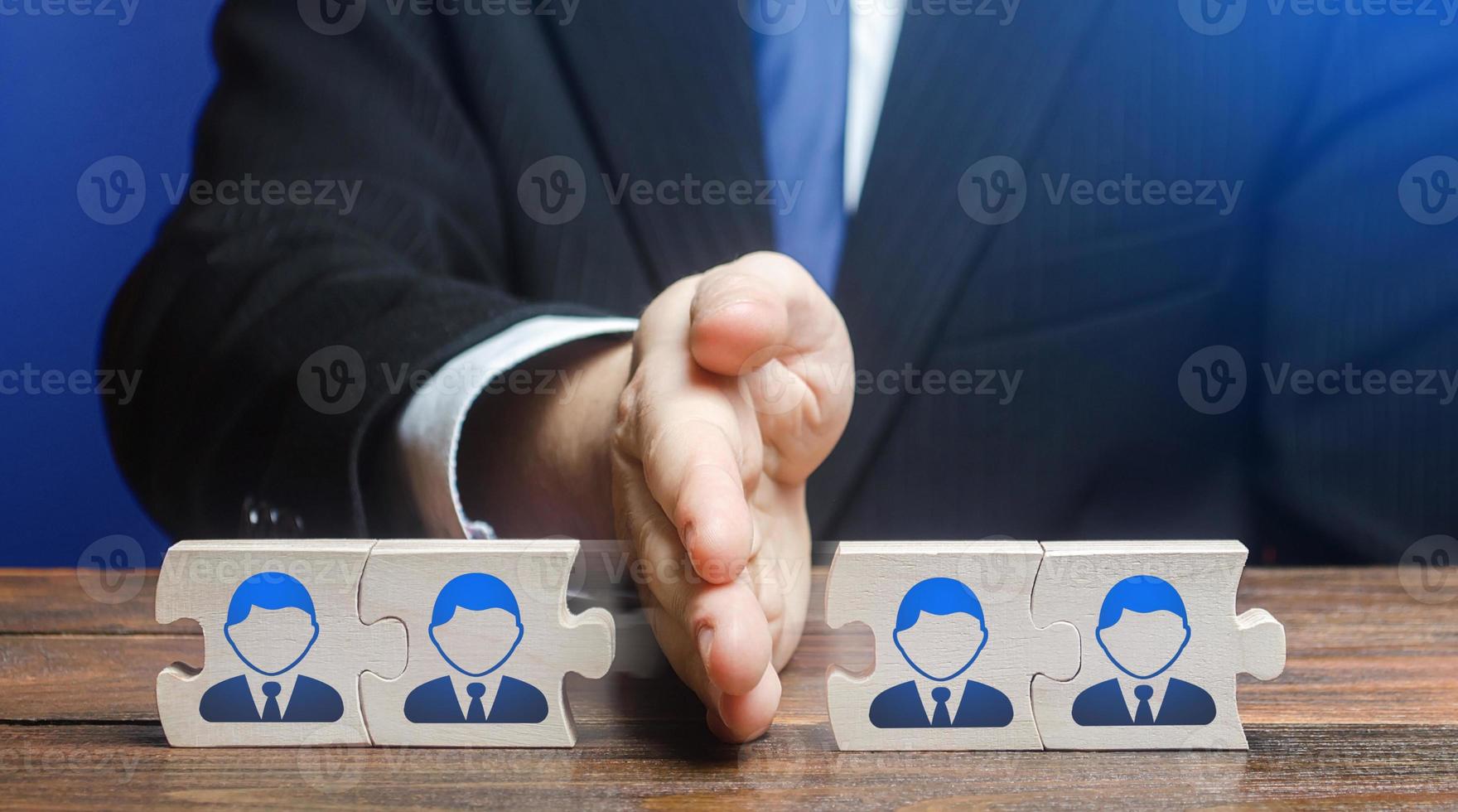 A man divides puzzle team of employees. Team split, structural fragmentation into small units. Improving company efficiency. Staff dismissal reduction. Distribution group members to parallel projects. photo