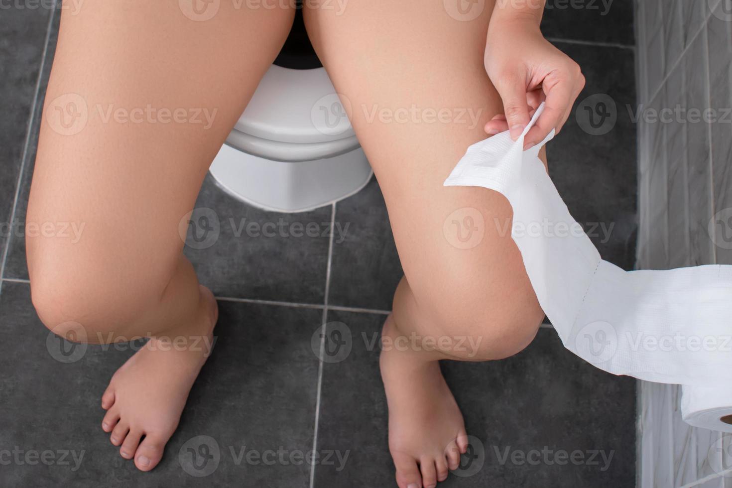 Top view. Asian people are sitting on the toilet bowl and carrying toilet tissue. photo