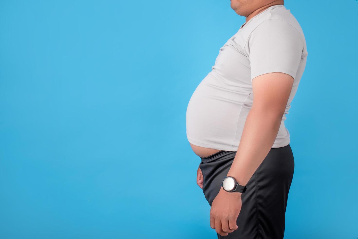 Fat man showing his belly on a blue background in the studio photo