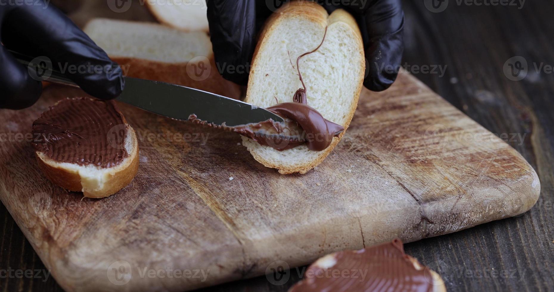 spread chocolate butter on a baguette, close up photo