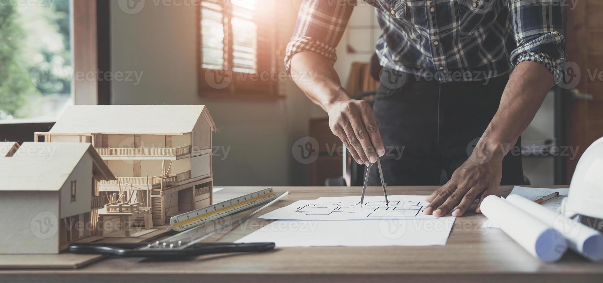 Concept architects, engineer holding pen pointing equipment architects On the desk with a blueprint in the office, Vintage, Sunset light.Selective Focus photo