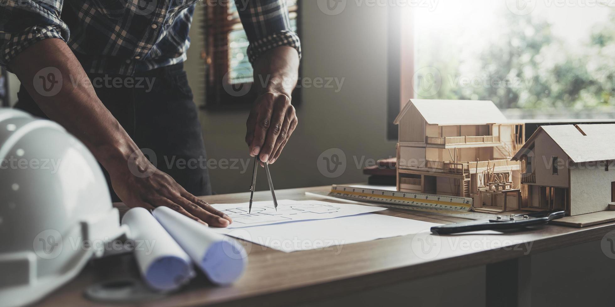 Concept architects, engineer holding pen pointing equipment architects On the desk with a blueprint in the office, Vintage, Sunset light.Selective Focus photo