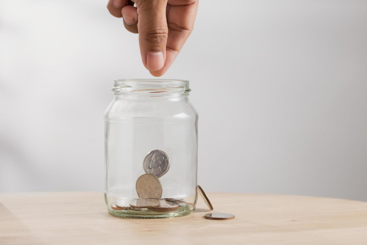 Saving money, Hand putting coin into a glass bottle photo