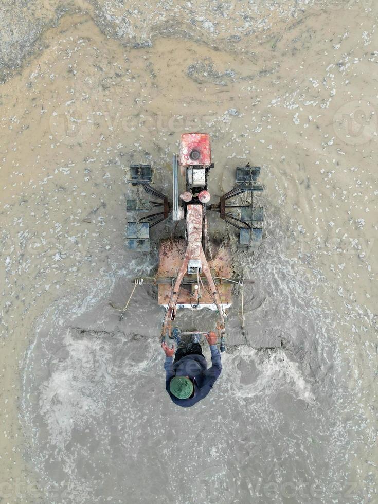 Aerial top down view farmer use tractor to plowing paddy photo