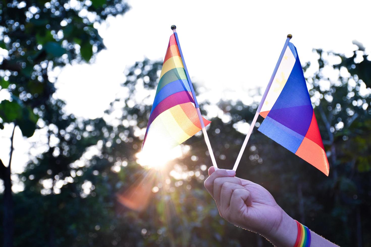 Rainbow flag and wristbands holding in hands, soft and selective focus, concept for lgbtq  genders celebrations and calling all people to respect human rights in pride month around the world. photo