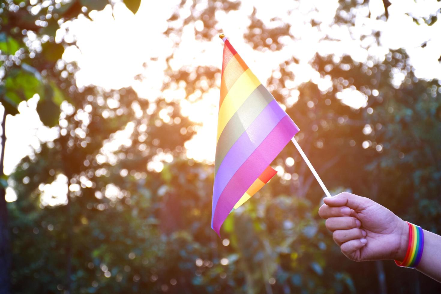 Rainbow flag and wristbands holding in hands, soft and selective focus, concept for lgbtq  genders celebrations and calling all people to respect human rights in pride month around the world. photo