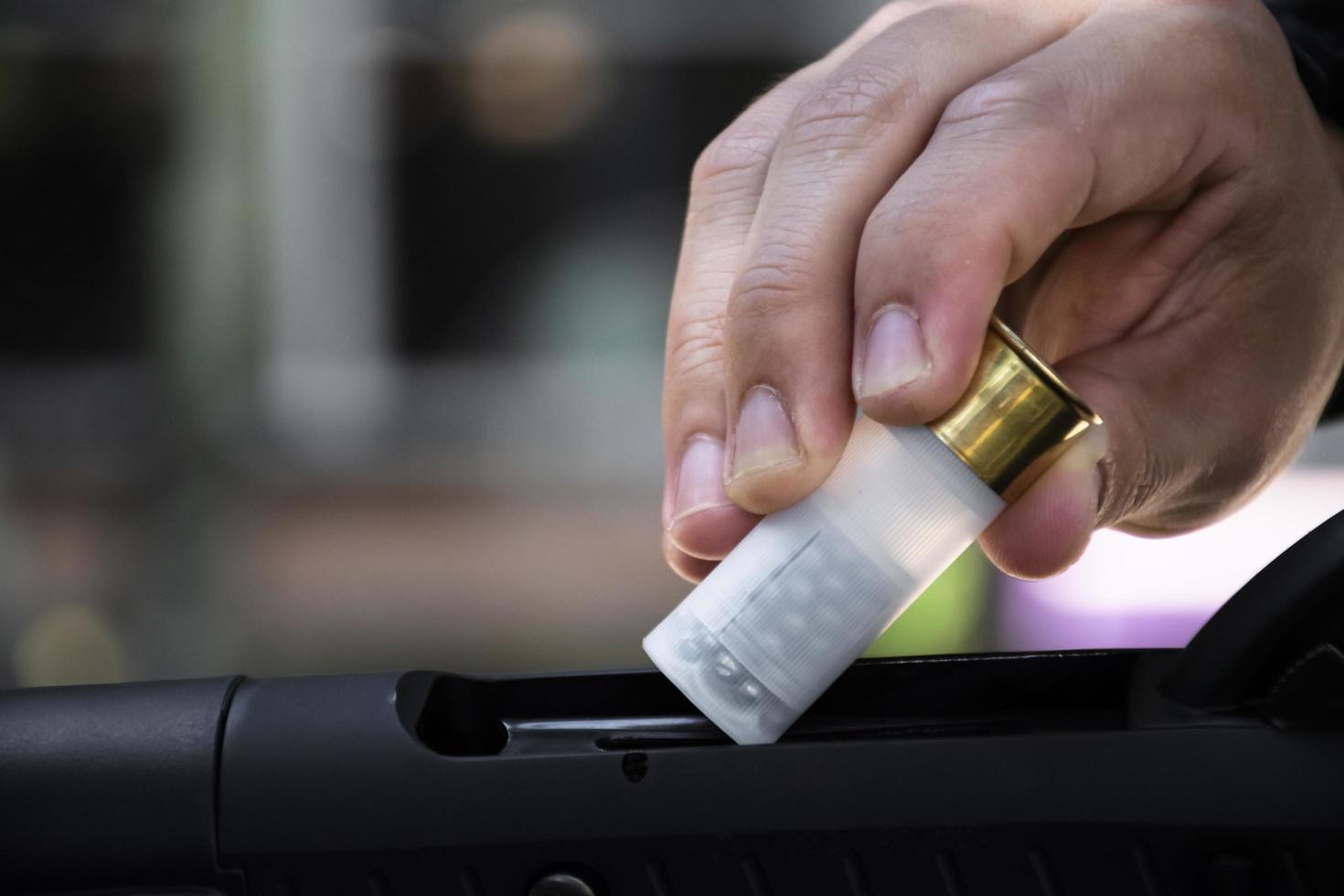 Shotgun man is inserting new shotshell bullets on shotgun, soft and selective focus. photo