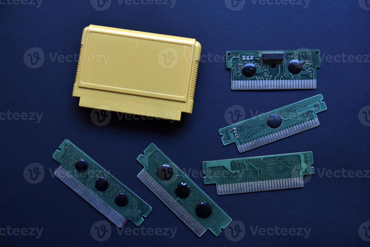 Electronic cartridge board for retro game console. A yellow plastic cartridge on a black background and an electronic board. photo