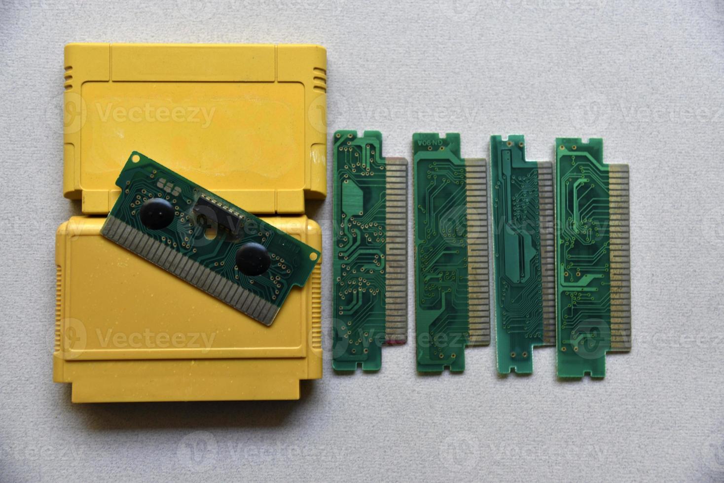 Electronic cartridge board for retro game console. A yellow plastic cartridge on a black background and an electronic board. photo