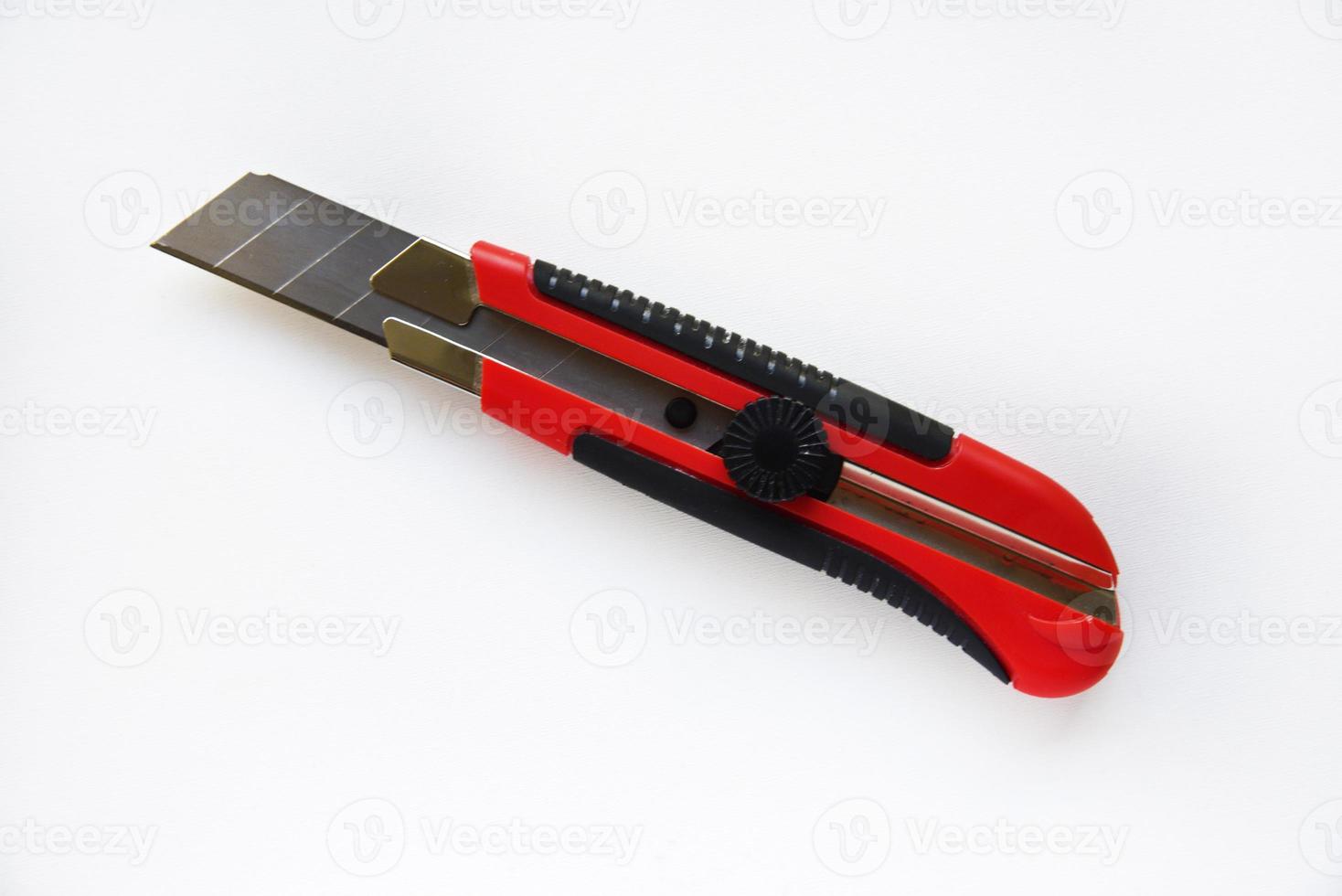 Red stationery knife with blades on a white background. Cutting tool with blades on a white background. photo