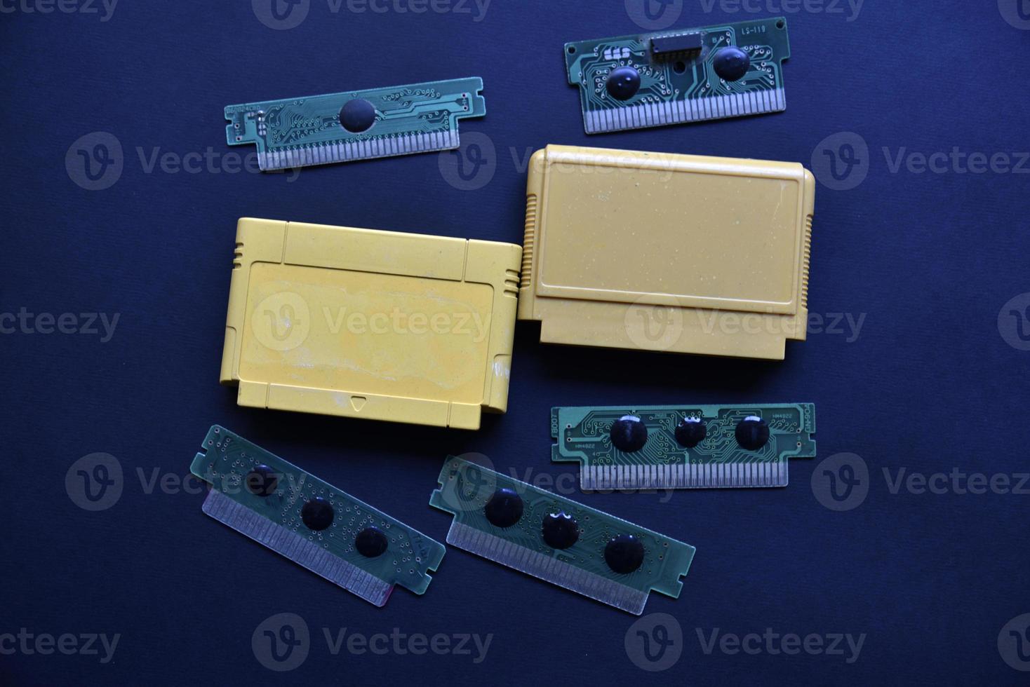 Electronic cartridge board for retro game console. A yellow plastic cartridge on a black background and an electronic board. photo