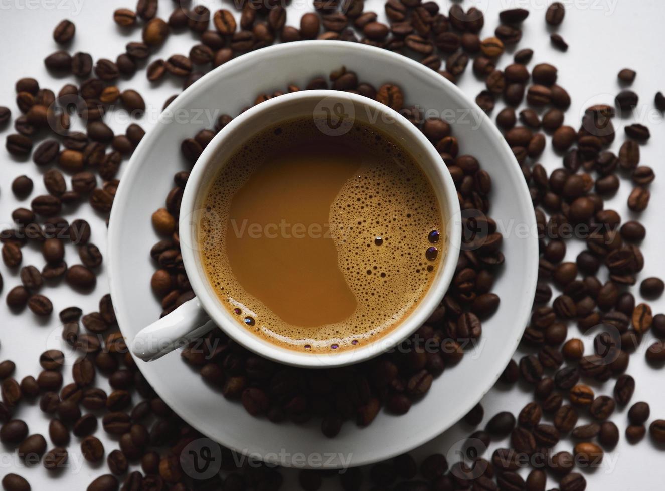 White porcelain cup with coffee and coffee beans on a white background. Tea pair with foamy coffee and coffee beans. photo