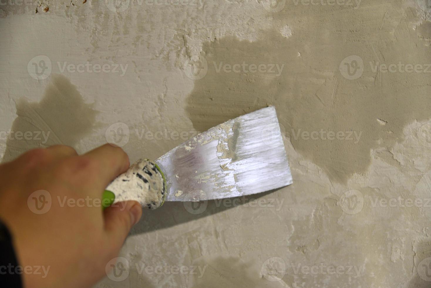 Work with an iron spatula when plastering the wall with a cement solution. Repair of the wall with a trowel with cement. photo