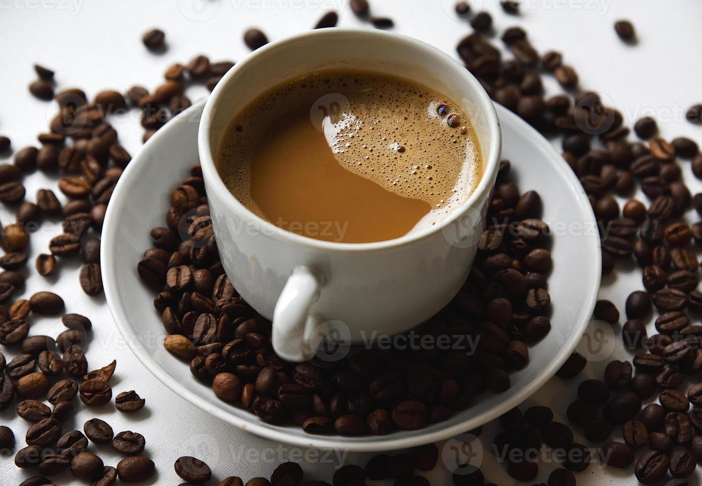 White porcelain cup with coffee and coffee beans on a white background. Tea pair with foamy coffee and coffee beans. photo