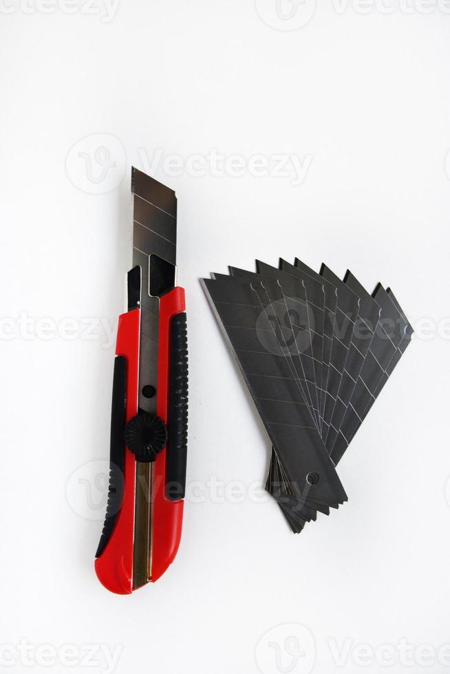 Red stationery knife with blades on a white background. Cutting tool with blades on a white background. photo