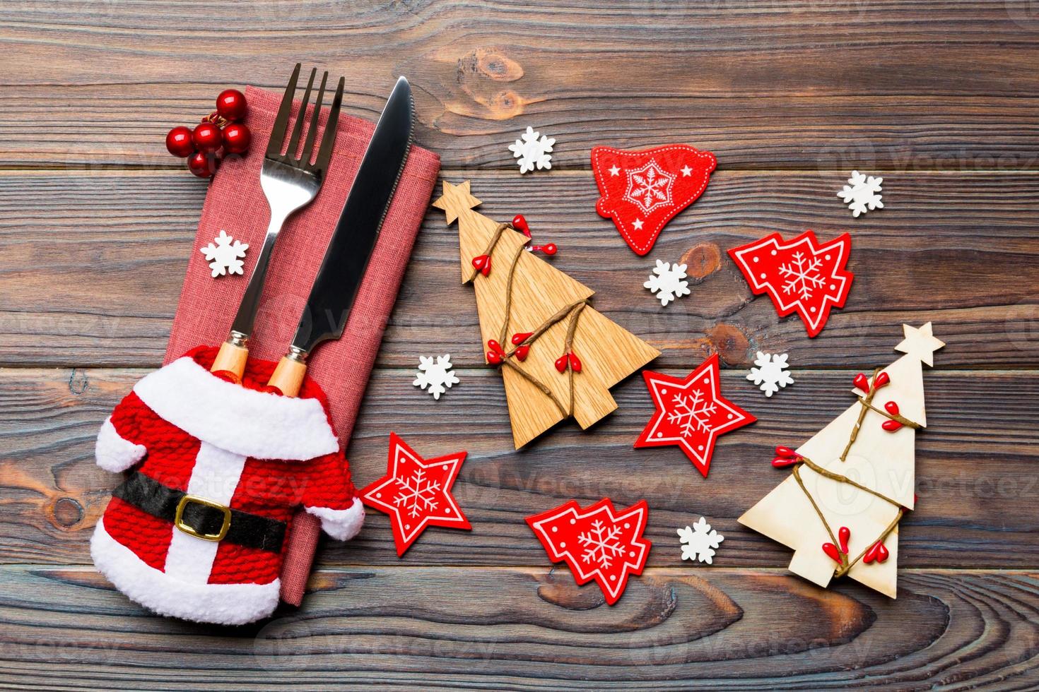 Top view of fork and knife tied up with ribbon on napkin on wooden background. Close up of christmas decorations and New Year tree. Happy holiday concept photo