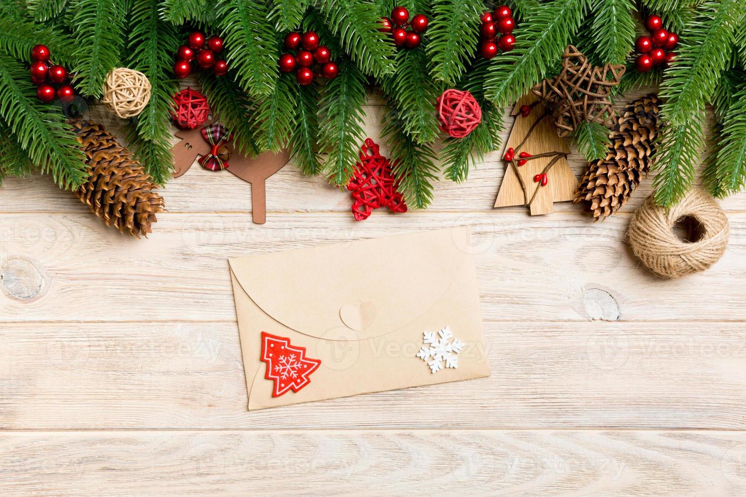 Top view of envelope, Christmas toys, decorations and fir tree branches on wooden background. New Year holiday concept photo