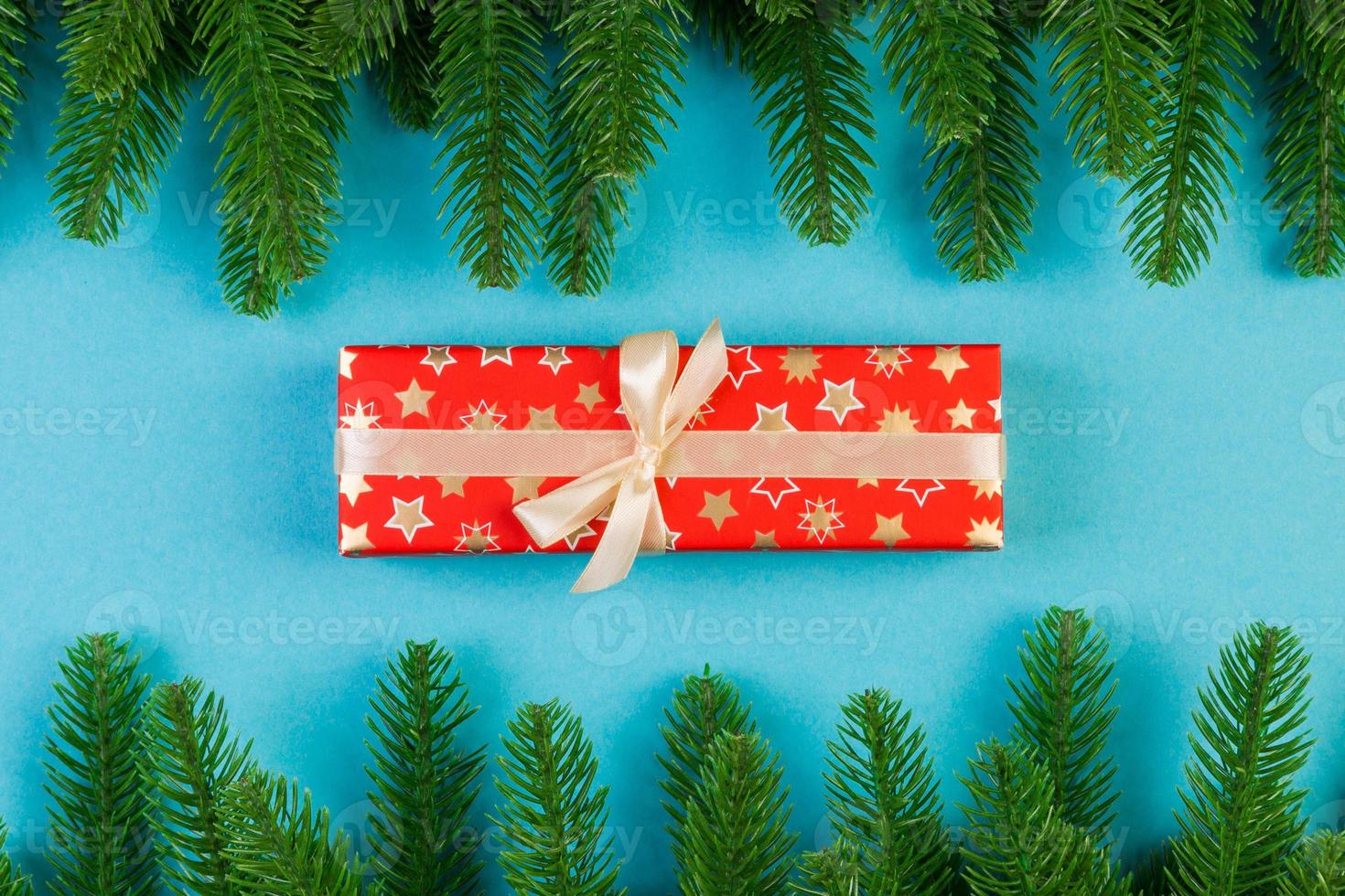 Top view of fir tree branches and gift box on colorful background. Christmas time concept with empty space for your design photo