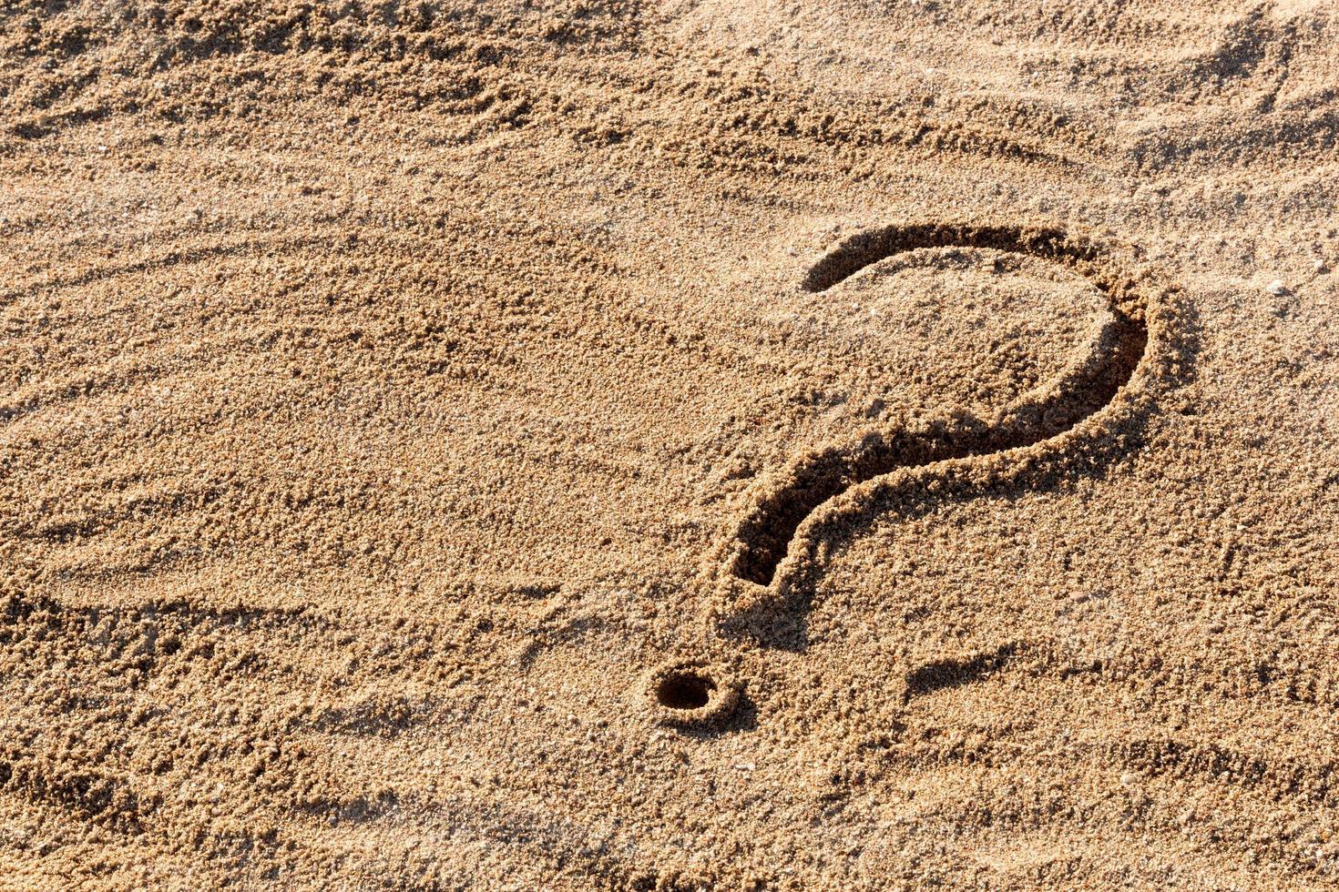 question marks written on beach sand close up, with copy space photo