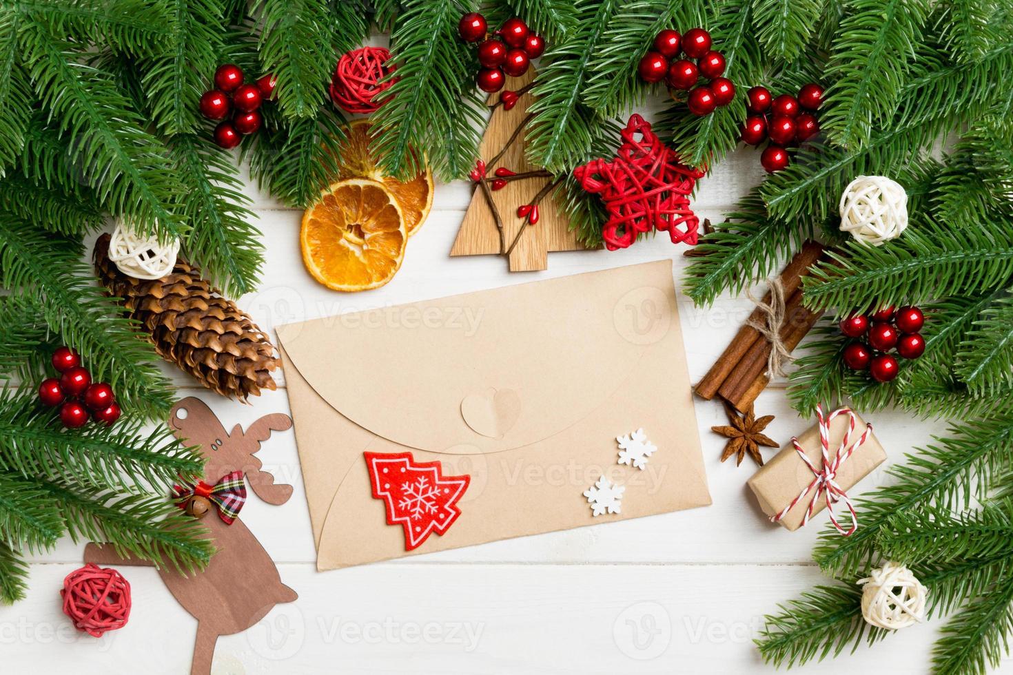 Top view of fir tree branches, envelope and festive decorative toys on wooden background. New Year time concept photo