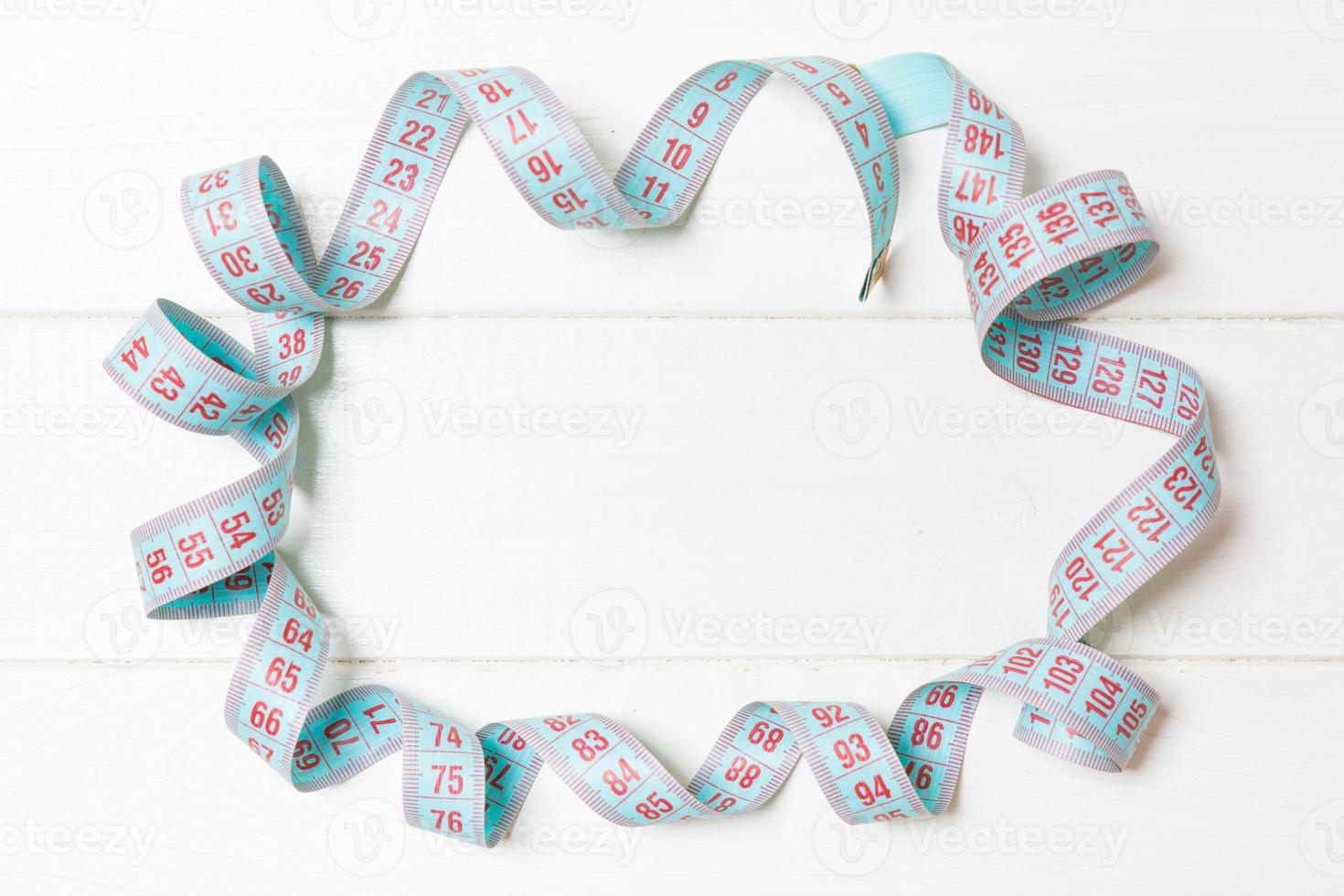 Top view of frame made of measure tape on wooden background. Keeping fit concept with empty space for your design photo