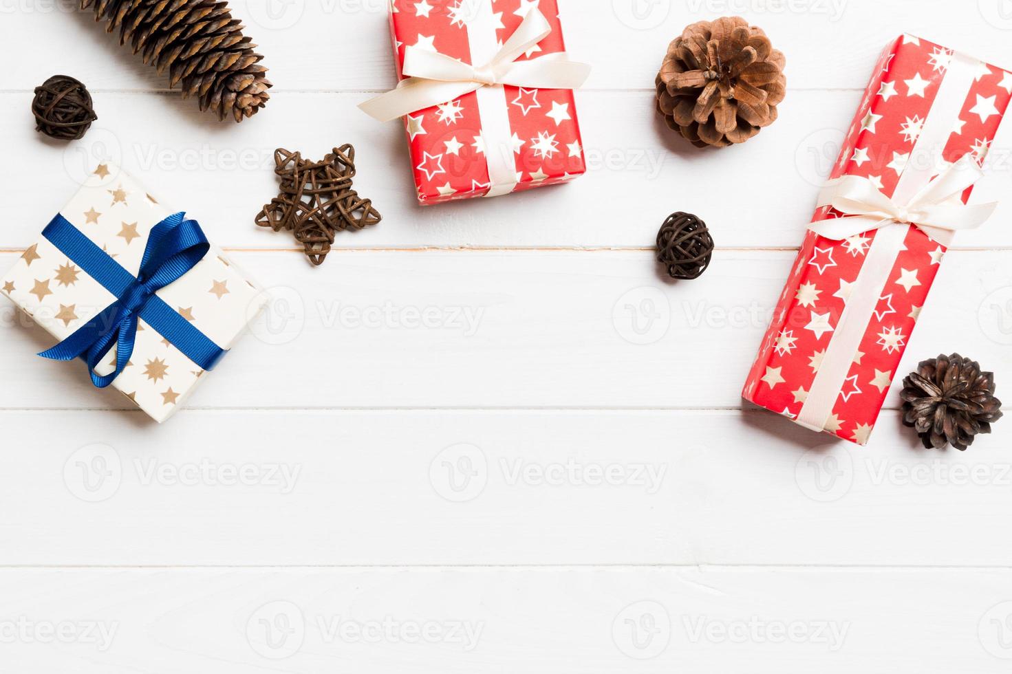 Top view of Christmas background made of gift boxes, pine cones and balls on wooden background. New year holiday concept with copy space photo
