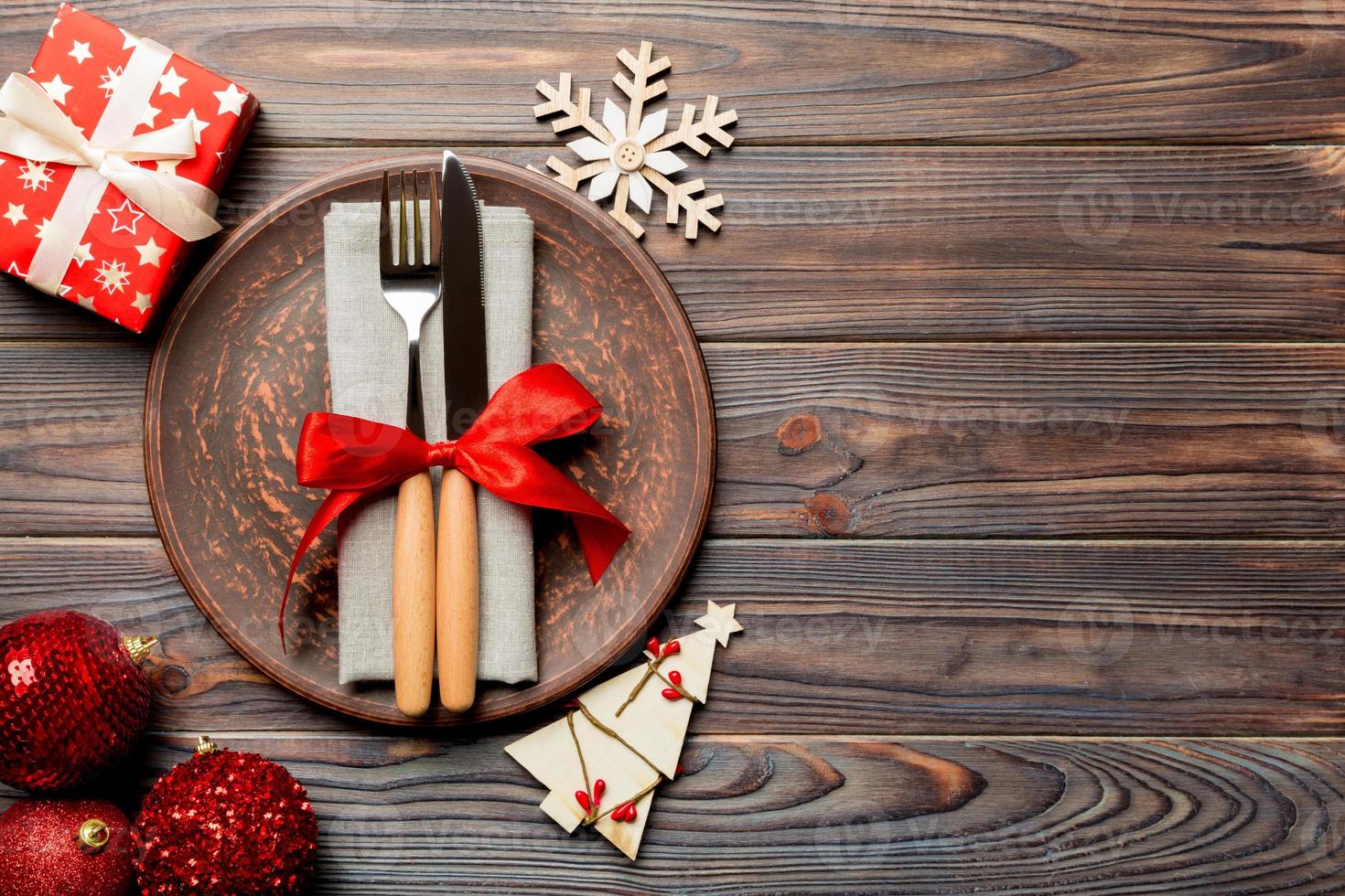 Top view of plate, fork and knife served on Christmas decorated wooden background. New Year Eve concept with copy space photo