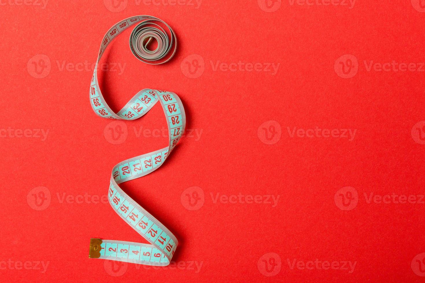Tangled measuring tape with space for your idea. Sewing and tailor concept on red background photo