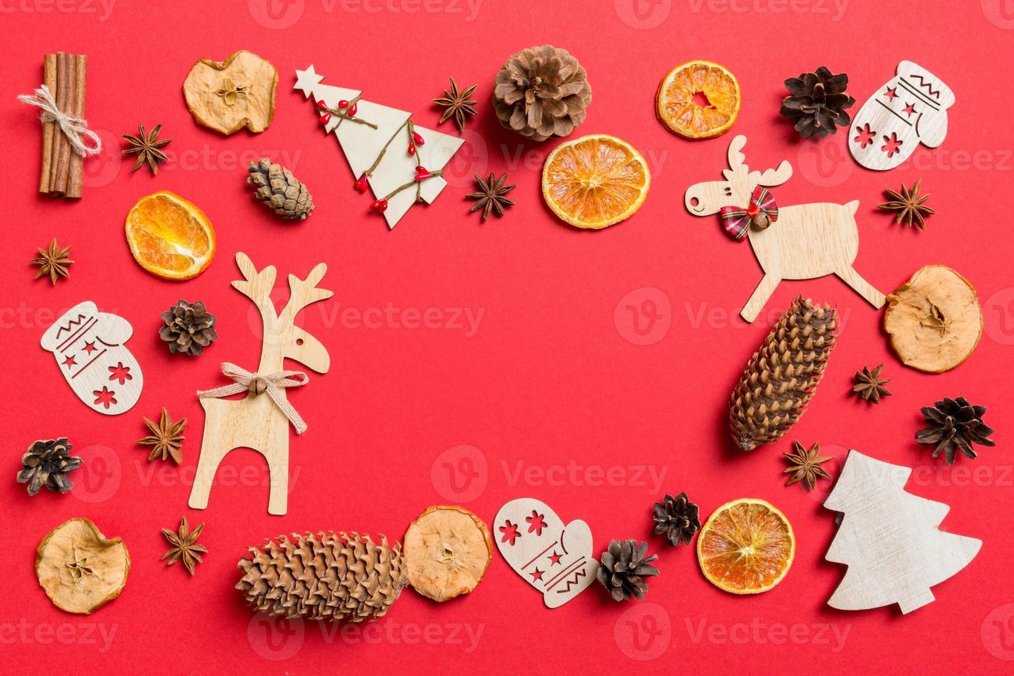 Top view of red background decorated with festive toys and Christmas symbols reindeers and New Year trees. Holiday concept with copy space photo