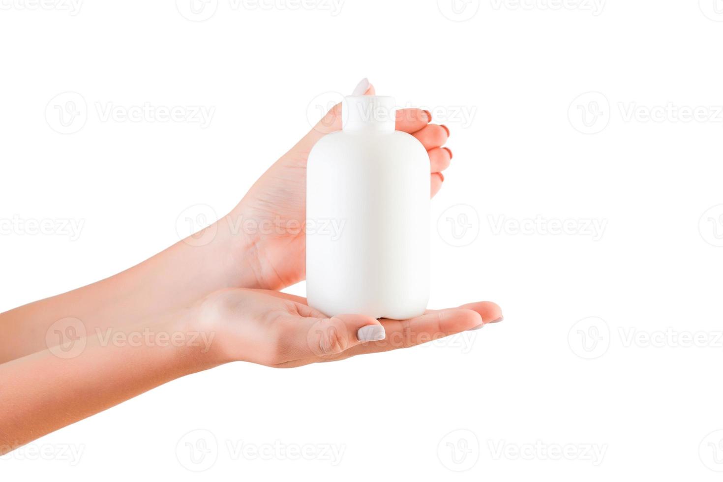 mano femenina sosteniendo una botella de crema de loción aislada. Chica dar tubo productos cosméticos sobre fondo blanco. foto