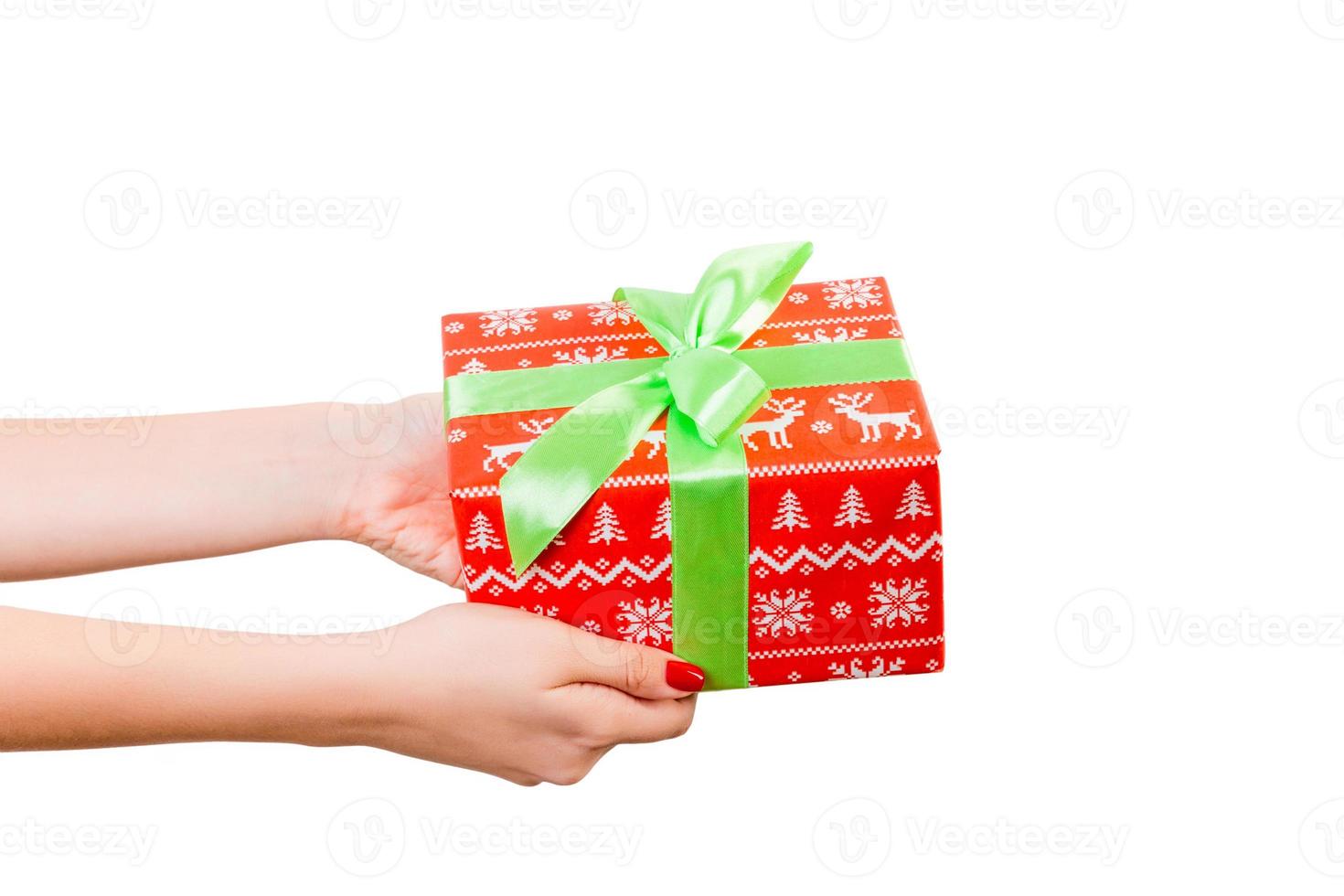 las manos de las mujeres dan Navidad envuelta u otro regalo hecho a mano en papel rojo con cinta verde. aislado sobre fondo blanco, vista superior. concepto de caja de regalo de acción de gracias foto