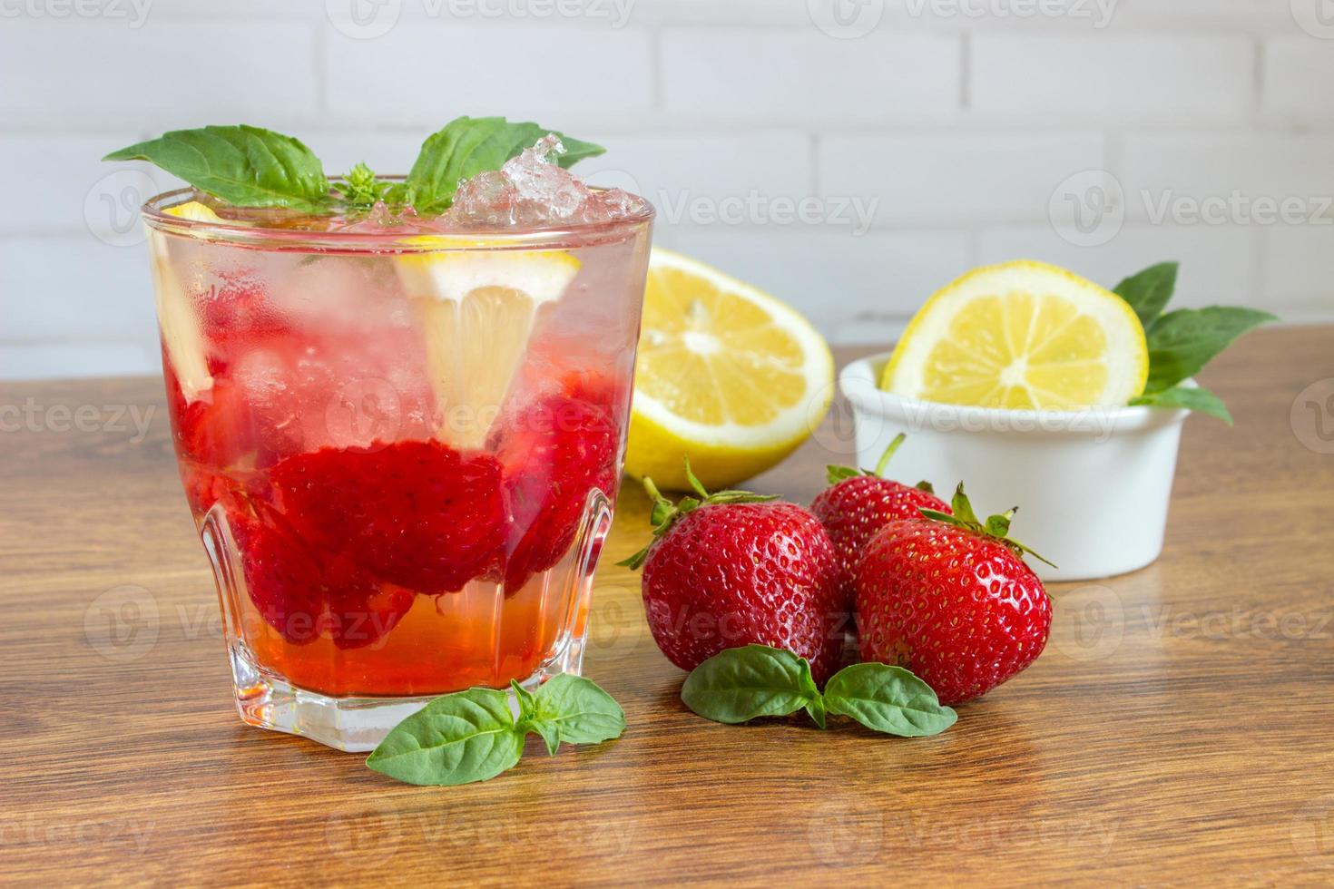 Glass of cold tea with mint,strawberry,lemon, on table photo