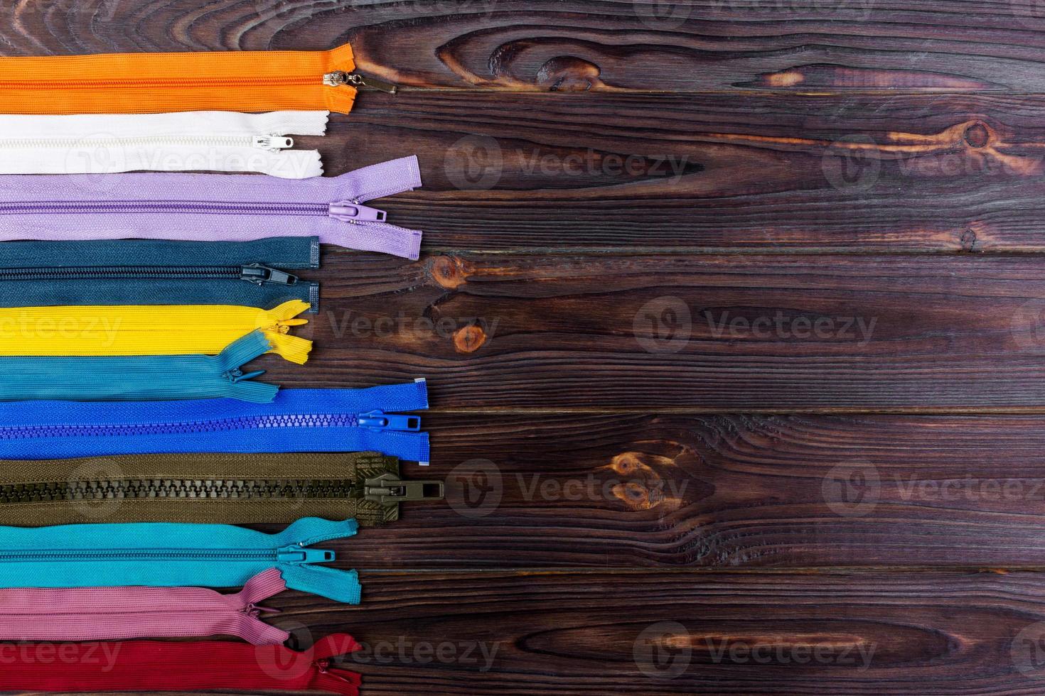 different colorful zippers in front of wood background photo