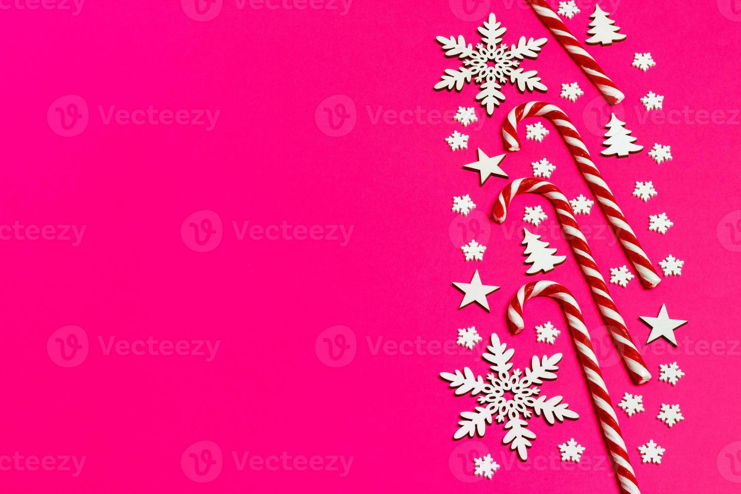 Christmas candy cane lied evenly in row on pink background with decorative snowflake and star. Flat lay and top view photo