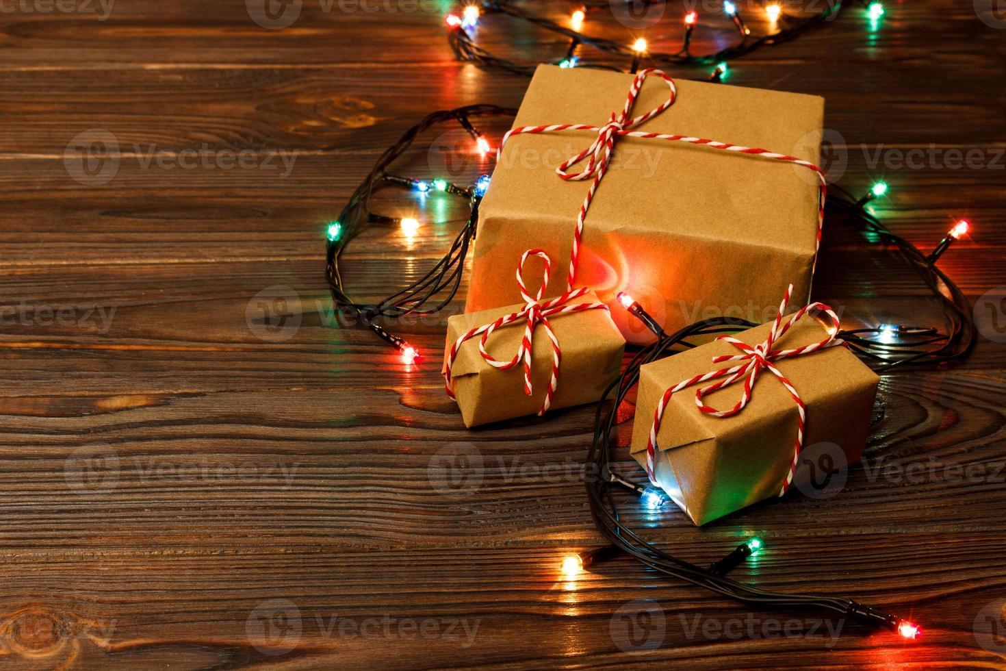 Christmas tree lights on the floor all around a nicely wrapped group of present boxes set under a Christmas tree photo