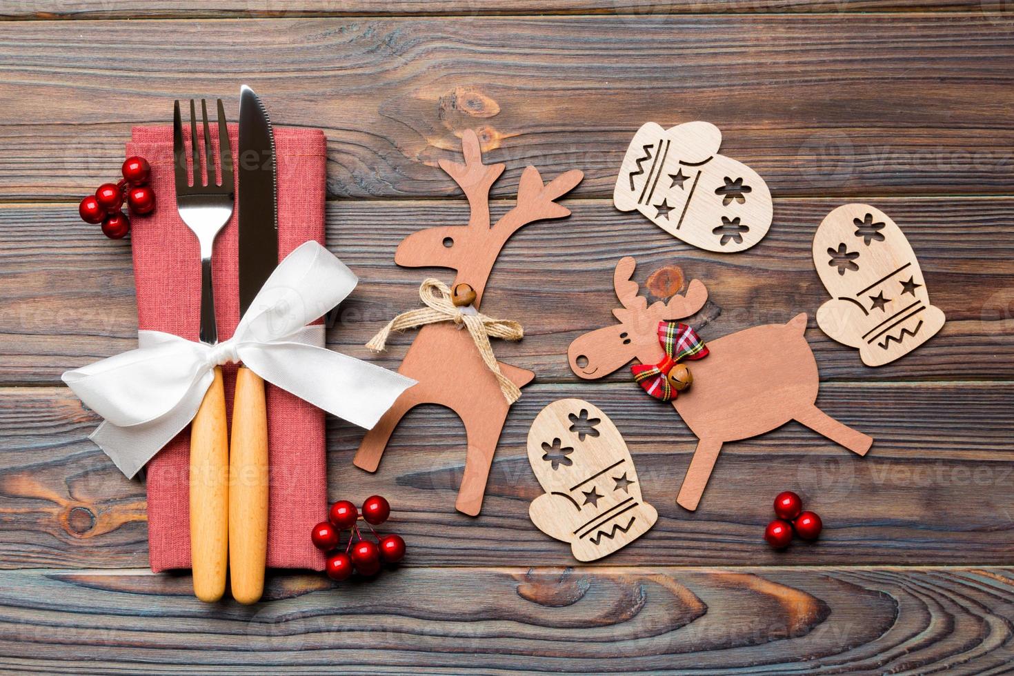 Top view of flatware tied up with ribbon on napkin on wooden background. Close up of christmas decorations and reindeer. New Year holiday concept photo