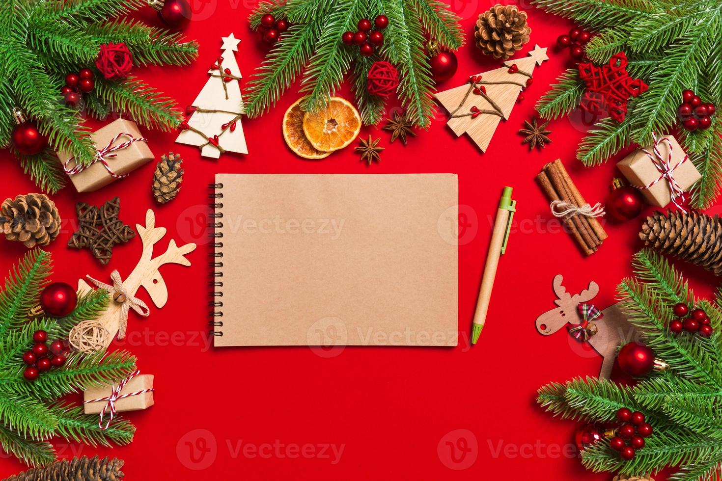Top view of notebook on red background made of Christmas decorations. New Year time concept photo