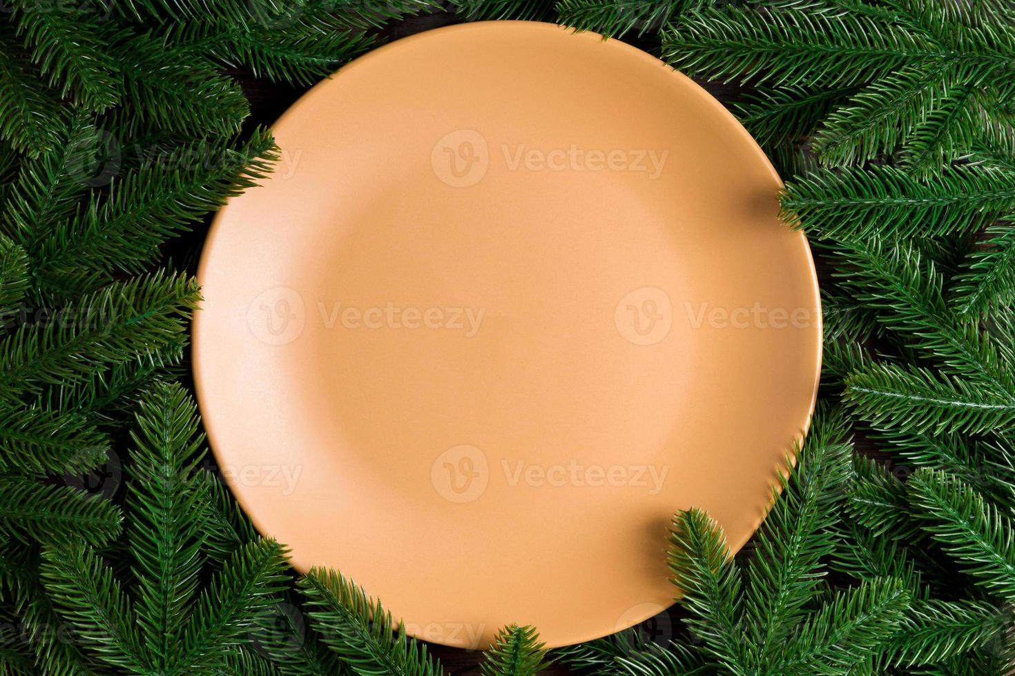 Top view holiday plate among green fir tree branches. Christmas dinner with copy space photo