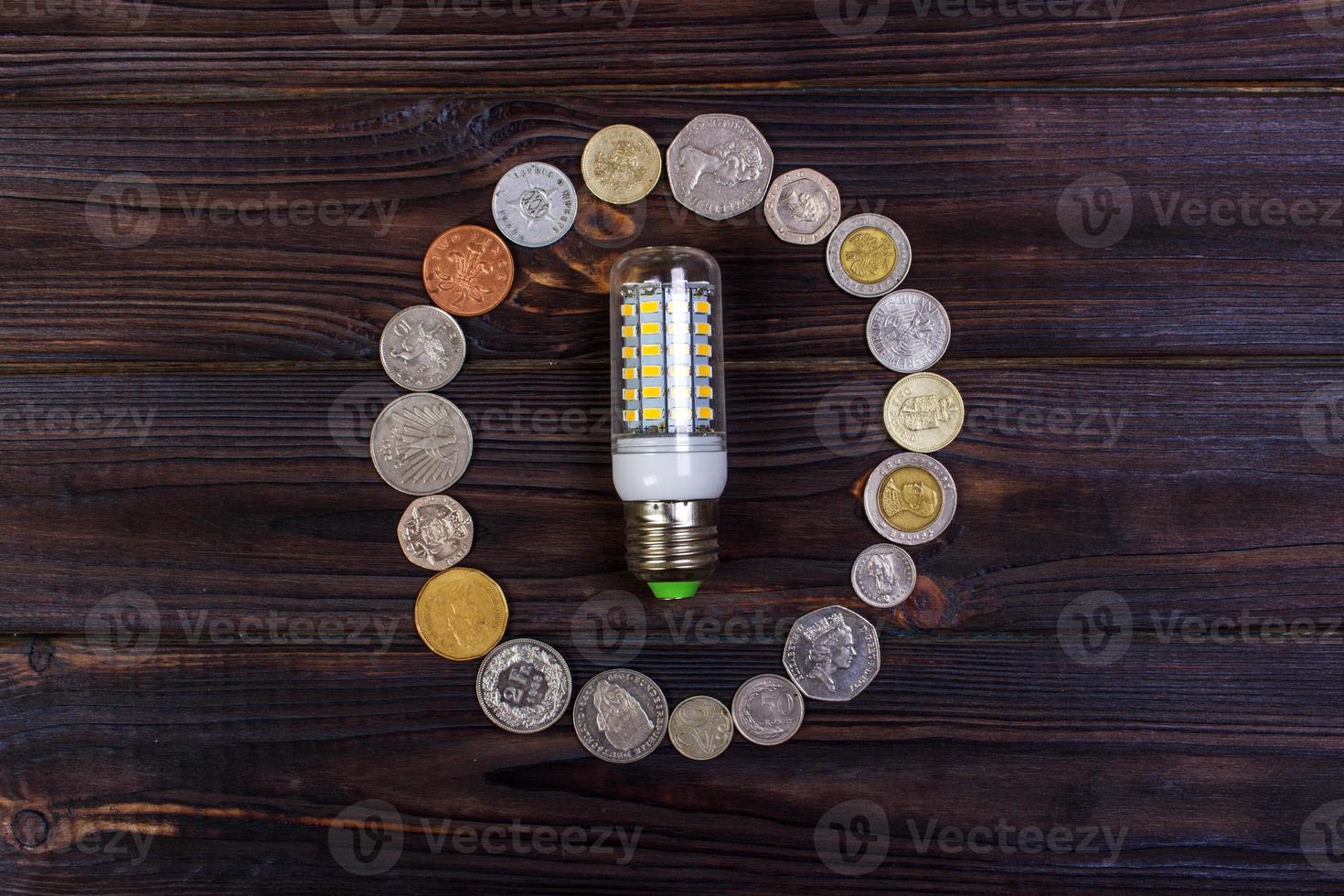 light bulb on over pile of coins - money, finance, savings concept and idea photo