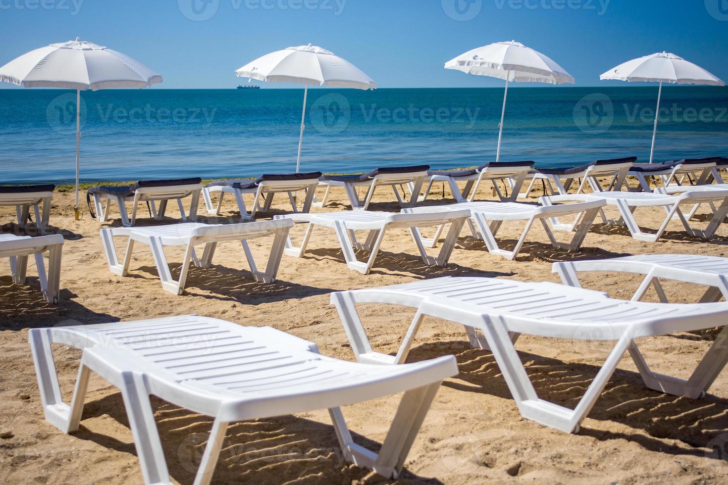 Beautiful empty beach with rows of sun beds under straw umbrellas photo